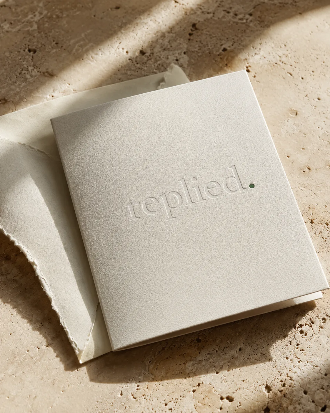 An embossed replied. invitation resting on travertine